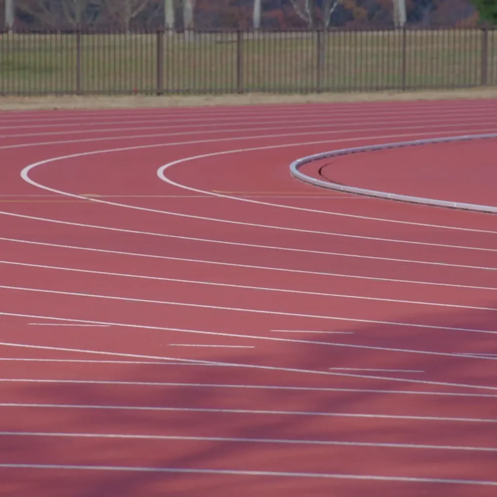 Basketball players in action under dramatic lighting, with the focus on a tense moment near the basket. The scene conveys a sense of intensity and competition.