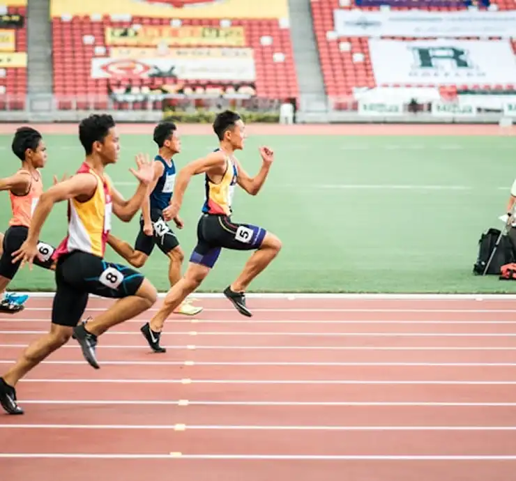 Une piste d'athlétisme rouge incurvée, avec des lignes de couloir blanches, qui se fond dans le gazon vert sur la gauche. Le lieu donne une impression d'ordre et semble prêt à accueillir des activités sportives.